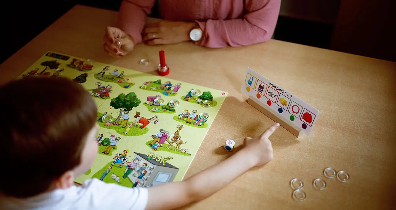 Kind und Logopädin spielen zusammen ein Spiel